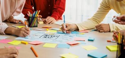 Creative business team brainstorming about marketing strategy and business plan by using mind mapping. Startup team work together to write down on paper. Focus on hand. Closeup. Variegated.